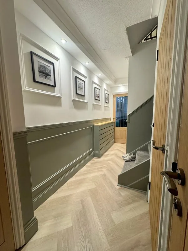 Renovated residential hallway with herringbone oak floor and wainscoting, London